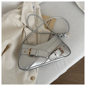 Detail of silver baguette bag with double strap buckles and golden metal hardware