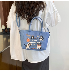 Detail of light blue denim tote with cat illustration and adjustable shoulder strap