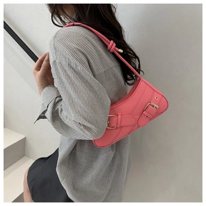 Detail of bright pink PU underarm bag with decorative straps and golden metal buckles