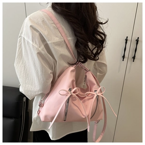 Detail der rosa Schleife und der silbernen Reißverschlüsse an einem glänzenden Rucksack