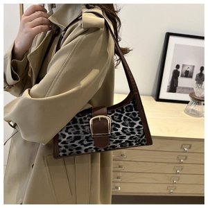 Dettaglio della borsa a spalla leopardata con fibbia dorata su cappotto beige