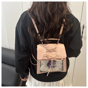 Pink ita bag detail with transparent window featuring white lace and bow accents