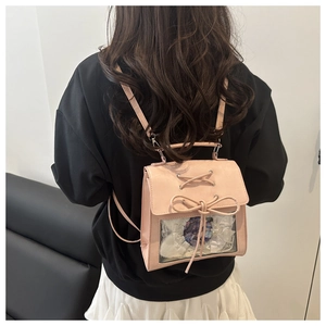 Detail of pink ita bag with transparent window, lace decoration, and ribbon bow tie