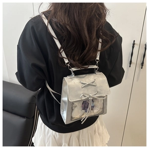 Detail of silver metallic ita bag featuring transparent window with purple flower and bows