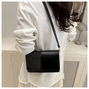 Détail de coutures contrastées et strass brillants sur un sac carré noir élégant