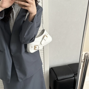 White faux leather crescent shoulder bag with vintage buckle straps and metallic eyelets
