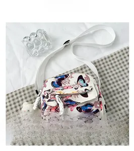 Detail of floral butterfly crossbody bag featuring a white plush bear pendant and zipper pocket