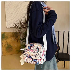 Detail of shell-shaped canvas crossbody bag with butterfly prints and plush charm