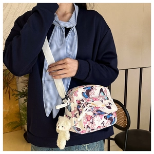 Close-up of nylon crossbody bag with colorful butterfly print and cute bear keychain charm