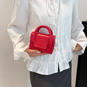 Mini red crocodile embossed crossbody bag with silver chain strap shown on a model