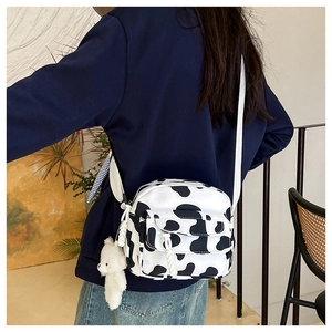 Detail view of the cow print nylon crossbody bag with cute white teddy bear charm