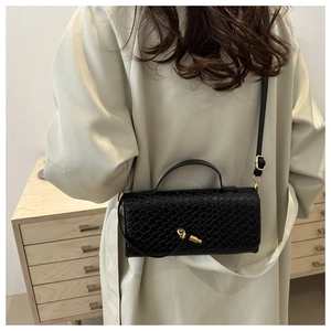 Detail of black snake pattern crossbody bag with gold buckle and adjustable strap