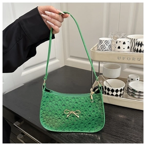 Détail du sac à bandoulière vert brillant avec nœud en métal doré et fermeture éclair