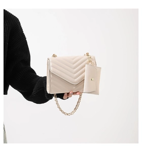 Quilted cream chain shoulder bag with detachable coin purse shown on a black sweater