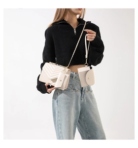 Detail of beige quilted chain bag set with gold hardware on a model with denim outfit