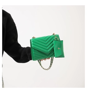 Detail of green quilted crossbody bag with golden chain strap and small coin purse attachment