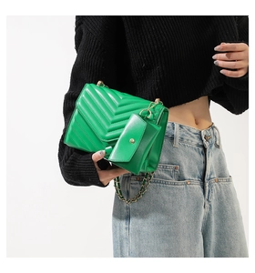 Detail of green chevron quilted shoulder bag with gold chain and mini pouch on model
