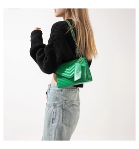 Detail of green V-quilted faux leather crossbody bag with chain strap and mini pouch