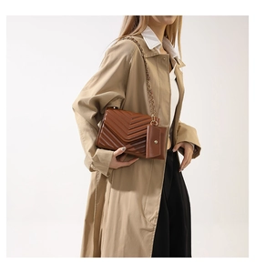 Detail of brown quilted crossbody bag with gold chain strap and mini coin purse