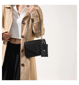Detail of black quilted chain bag with matching coin purse on a fashion model