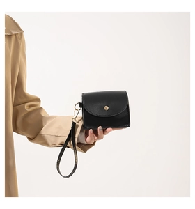 Close-up of black quilted leather mini coin purse with wristlet strap and round metal clasp