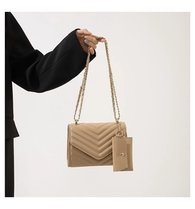 Detail of beige quilted chain handbag with matching mini pouch on a black suit jacket