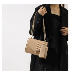 Detail of beige quilted chain shoulder bag with matching mini pouch and gold hardware