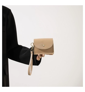 Close-up of beige leather mini coin pouch with gold snap button and wristlet strap