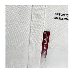 Detailed close-up of white canvas tote bag material texture with red brand logo patch