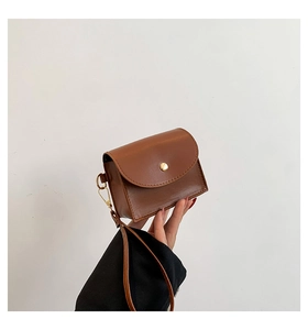 Detail of caramel brown quilted mini crossbody bag with golden bead magnetic closure