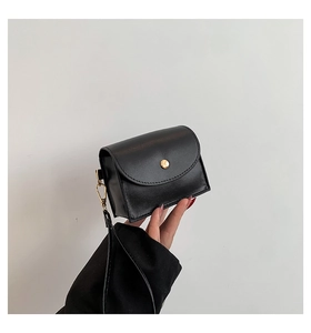 Detail of a mini black quilted leather bag with a round gold metallic snap fastener