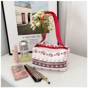 Detalle de bolsa de maquillaje acolchada con asa roja y lindos motivos de casas pequeñas