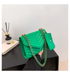 Detail of green quilted crossbody bag with golden chain and detachable mini pouch