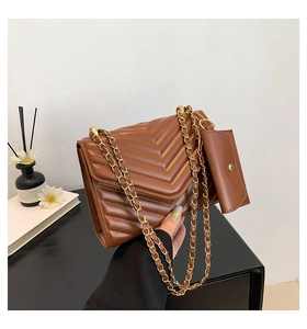 Detail of brown quilted shoulder bag with chevron pattern and gold chain strap