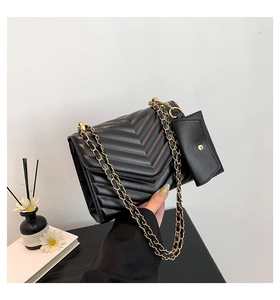 Close-up of black V-quilted faux leather shoulder bag with gold chain and small pouch