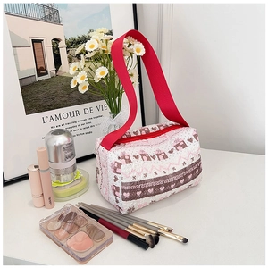 Detalle del neceser acolchado con correa roja y accesorios cosméticos en la escena