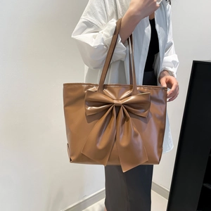 Large capacity brown tote bag with bow detail and slim shoulder straps on model