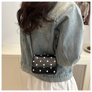 Detailed side view of a mini black crossbody bag with white polka dot patterns