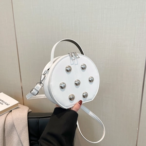 Sac bandoulière blanc circulaire avec rivets argentés en étoile et poignée supérieure