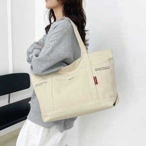 Minimalist beige canvas tote bag with large capacity shown on casual female model