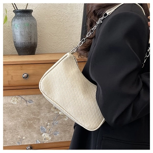 Close-up of minimalist beige woven handbag with stylish silver metal chain strap detail