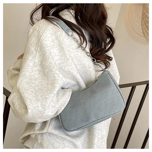 Detail of grey corduroy baguette bag with silver chain strap worn by a model