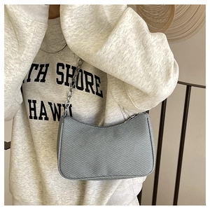 Detail of denim texture shoulder bag with chunky silver chain and zip closure