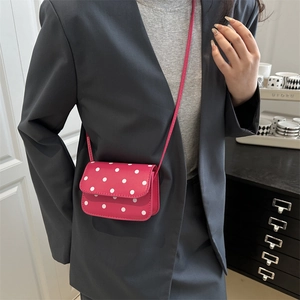 Mini hot pink crossbody bag with white polka dots and long shoulder strap on model