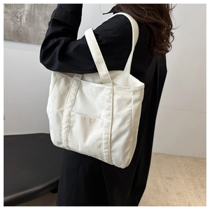 Detail of white corduroy tote bag showing soft ribbed texture and minimalist front pocket