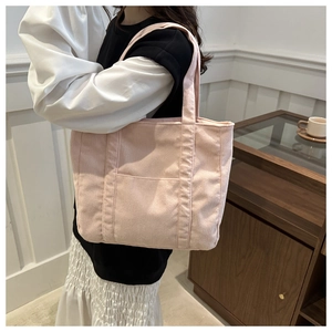 Close-up of pink corduroy tote bag featuring vertical ribbed texture and front pocket