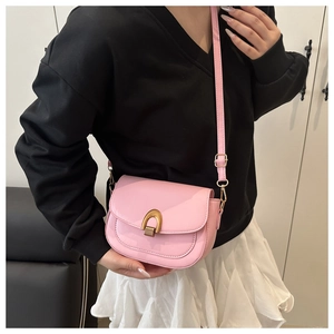 Vue détaillée d'un sac besace rose vif avec boucle fer à cheval dorée sur un mannequin