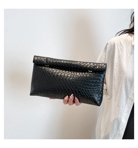 Détail de la texture tressée noire sur la pochette en cuir avec boucle dorée élégante