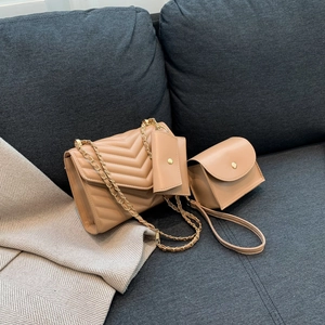 Three-piece beige quilted crossbody bag set with chain strap and mini pouch on sofa