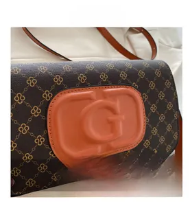 Macro shot of dark brown textured bag with diamond chain pattern and orange G letter detail